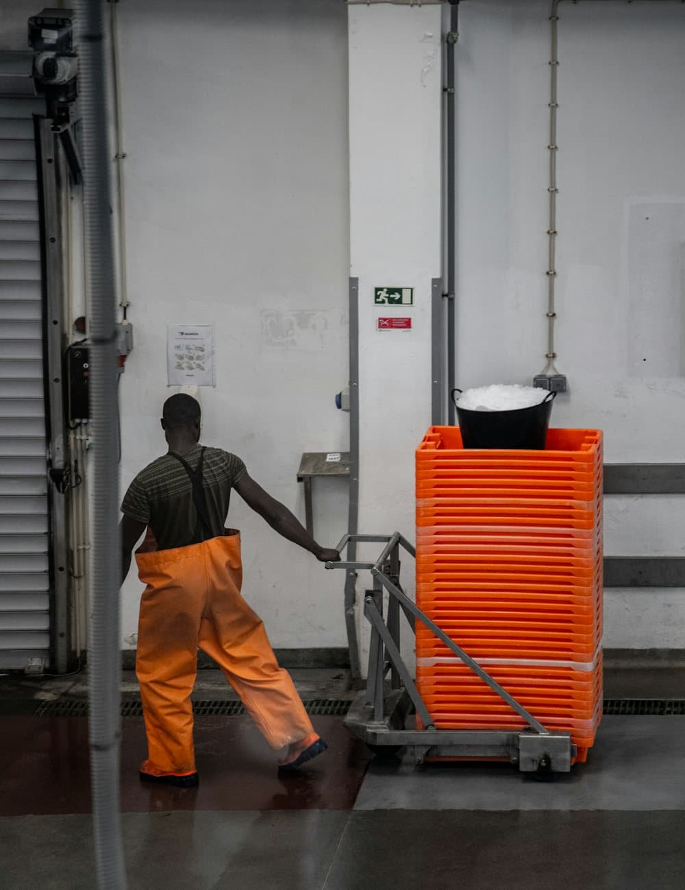 A general labourer hauling a cart of orange crates