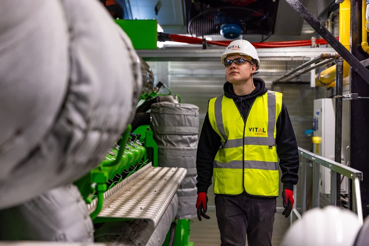 A worker in a yellow hi-vis vest walking through a plant room