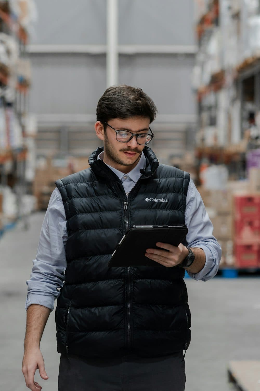 A supervisor walking a warehouse aisle with a tablet